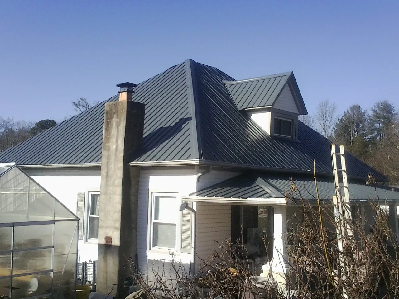 Dark blue standing seam metal roof on a white farmhouse with dormer — Slate & Tile Roof Repair by Roofing Brothers in Kankakee