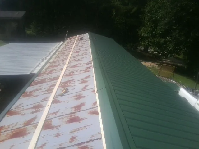 Old rusted panels beside newly installed green metal roofing — Wind Damage Roof Repair by Roofing Brothers in Kankakee