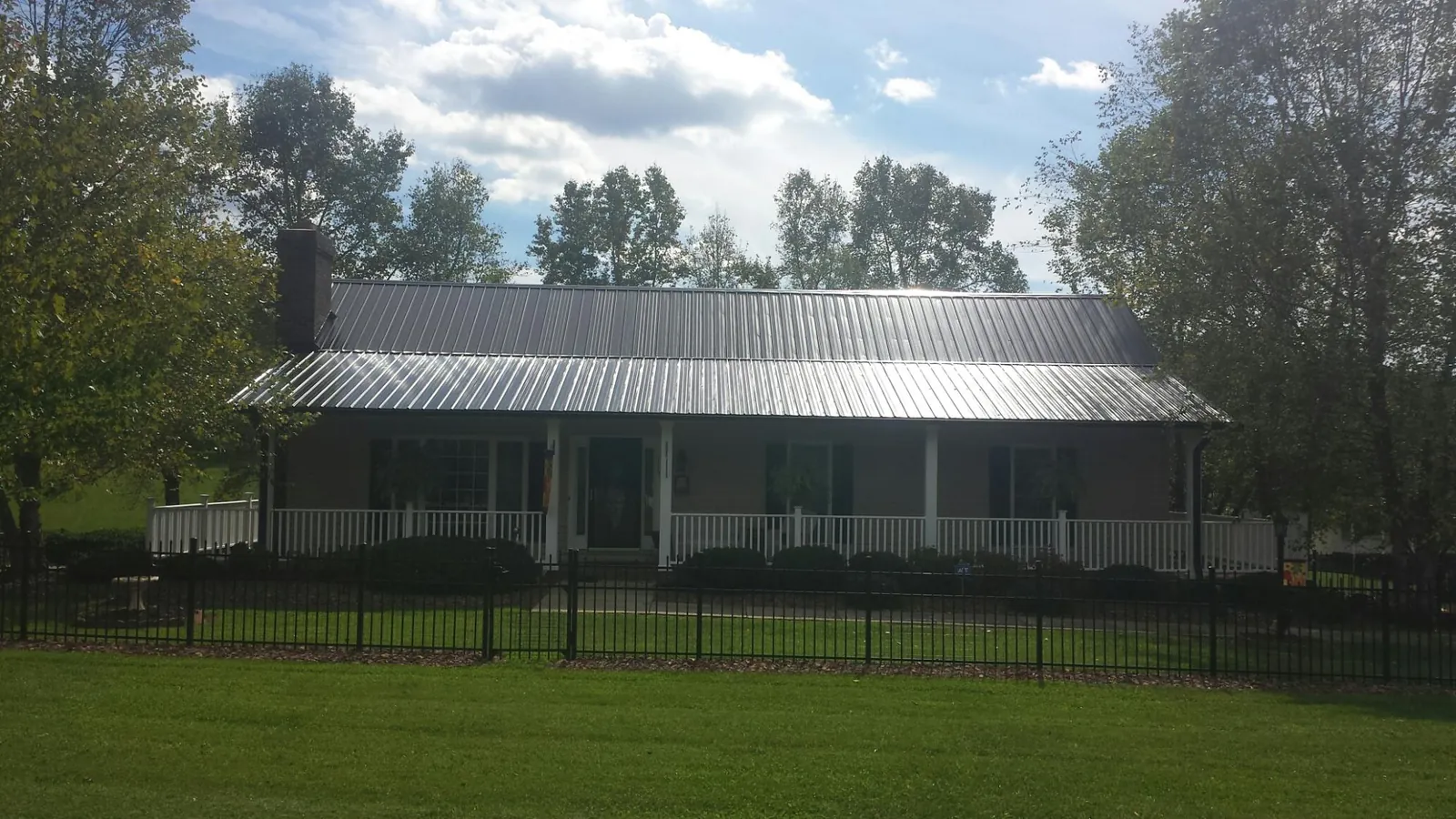 Gray metal roof on a brick ranch with a full width front porch — Gutter Guard Installation work by our crew in Kankakee