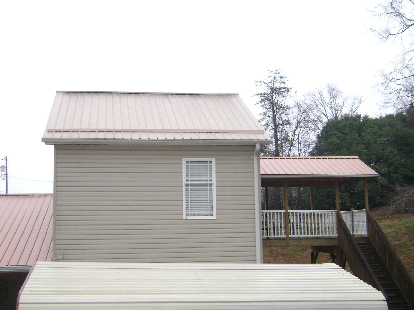 Tan metal roofs on a two story addition and attached porch, from a Roof Replacement job in Kankakee