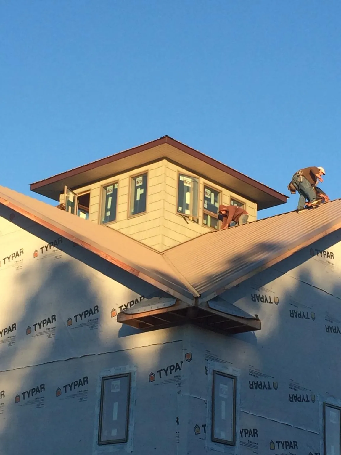 Roofers working around a rooftop cupola on a new metal roof at sunset — Roof Waterproofing in Kankakee by Roofing Brothers